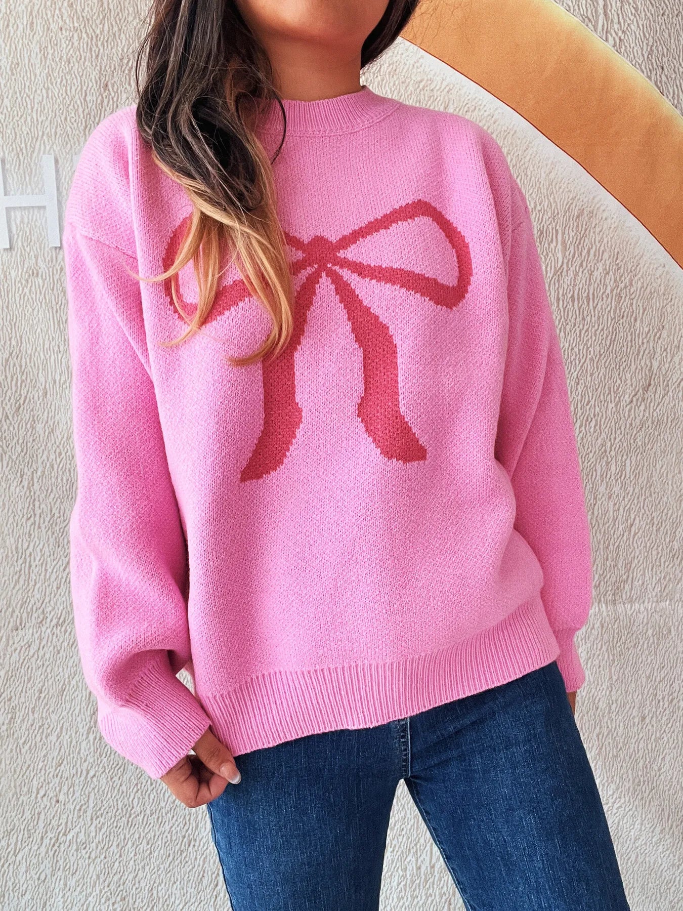 Stylish bow pattern casual long sleeve sweater in pink, perfect for effortless everyday wear. Model highlighting its cozy fit.