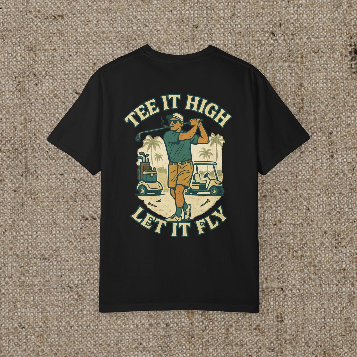 Tee It High Let It Fly Graphic Tee featuring a golfer swinging a club against a tropical background, perfect for golf enthusiasts.