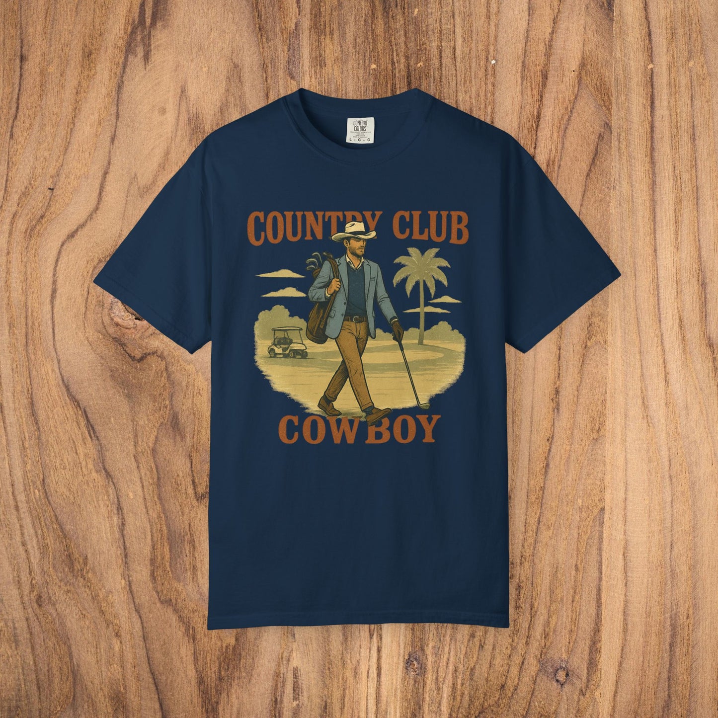 Flat lay of the Country Club Cowboy Graphic Tee on a wooden surface, highlighting the stylish graphic design and quality fabric.
