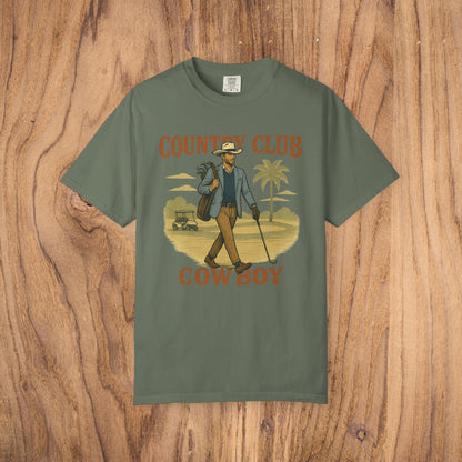Country Club Cowboy Graphic Tee in olive green showcasing a cowboy strolling with a golf bag against a palm tree background, made of durable cotton fabric, with a comfortable ribbed collar and eco-friendly crewneck.