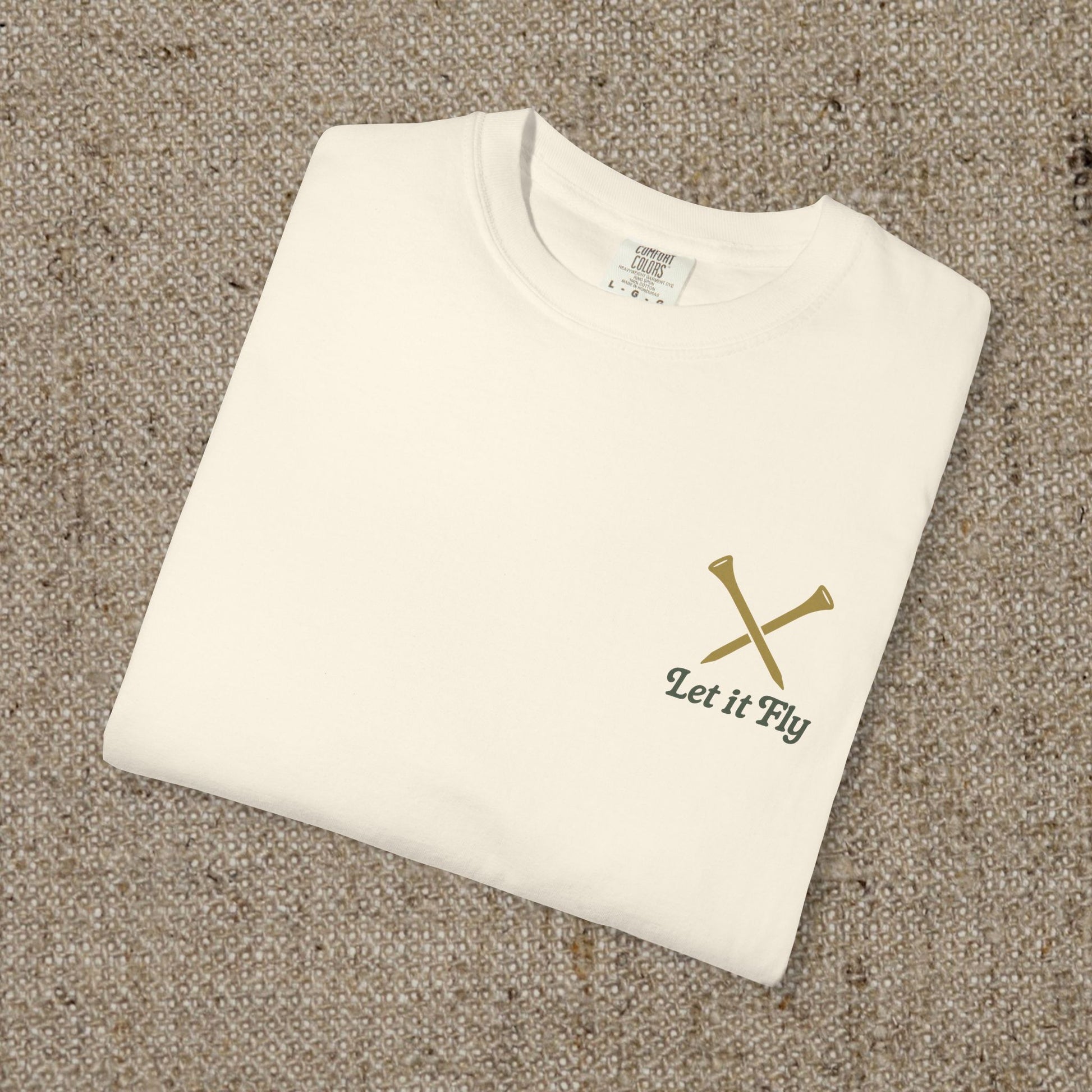 Tee It High Let It Fly Graphic Tee in soft US cotton, showcasing a minimalistic design with crossed golf clubs on a beige background, perfect for a stylish casual look.