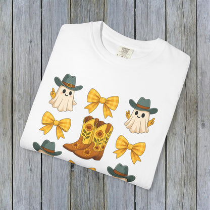 Cute Halloween T-Shirt design displaying playful ghosts, yellow bows, and cowboy boots, presented neatly folded against a rustic wooden backdrop, ideal for eco-conscious fall fashion.