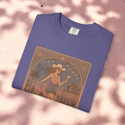 Line Dancer Tarot Tee in a rich purple hue, crafted from soft cotton and displaying a unique illustration of a cowboy hat-wearing woman dancing amidst desert elements. Ethically made and available in sizes S-4XL.