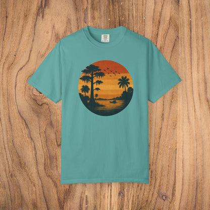 Unisex Garment-Dyed Sunset Tee in teal featuring a sunset motif with palm trees, designed for comfort and style, available in sizes S to 4XL.