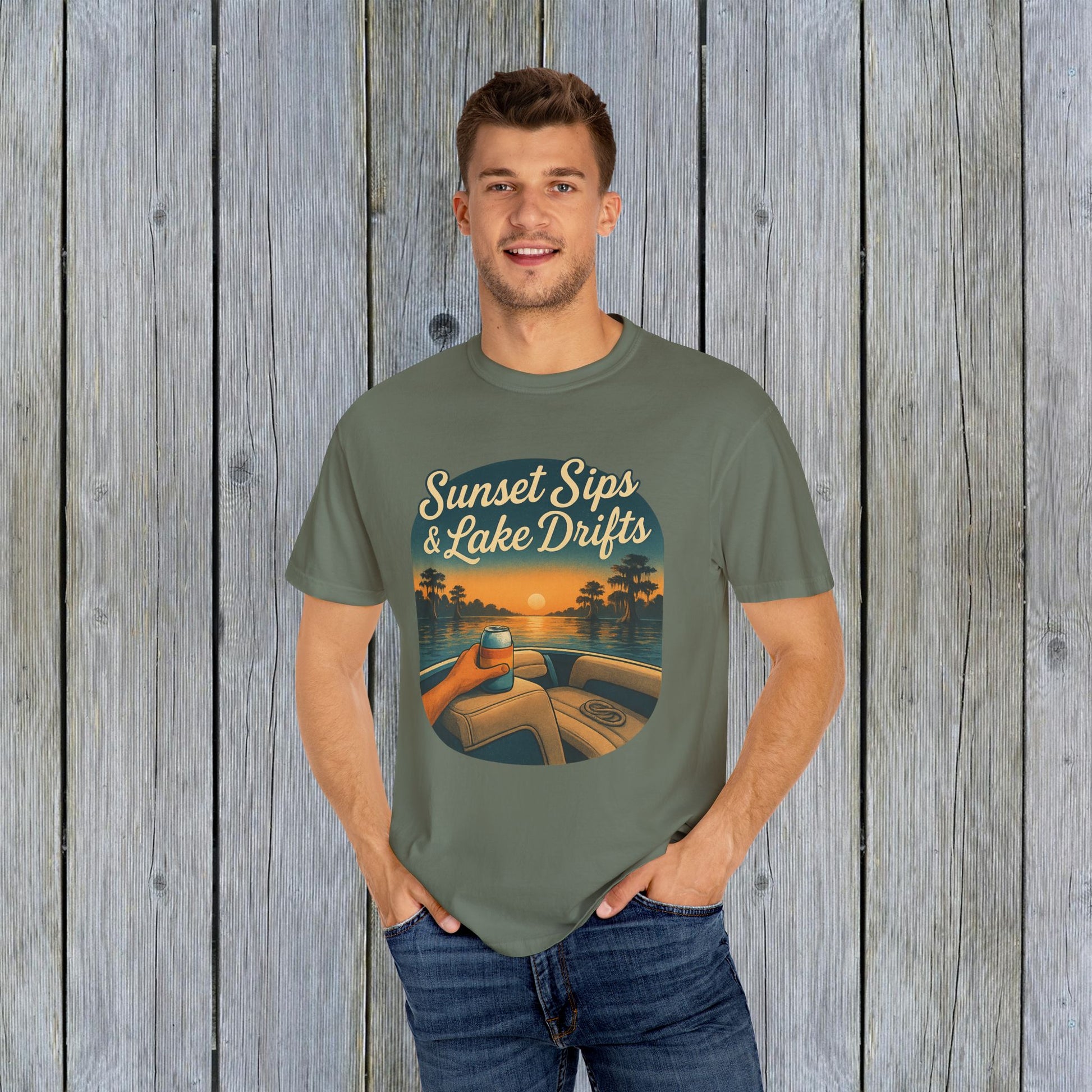 Model wearing Lake Drifts T-Shirt in olive green, showcasing the sunset sips and lake drifts graphic, made from soft 100% US cotton.