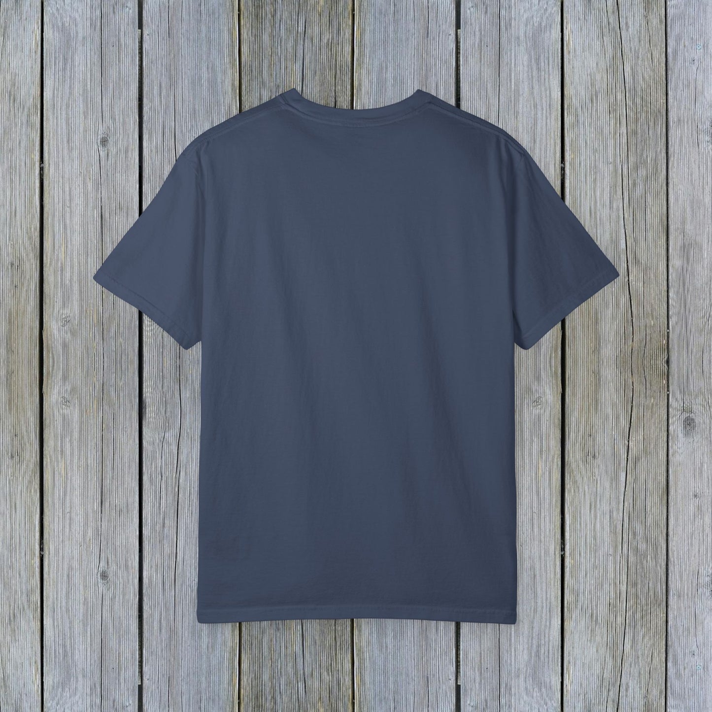 Back view of the Unisex Garment-Dyed Lake Rules Tee - Soft Vintage Fabric, Sizes S to 4XL, perfect for outdoors, showcasing its simple style against a wooden backdrop.