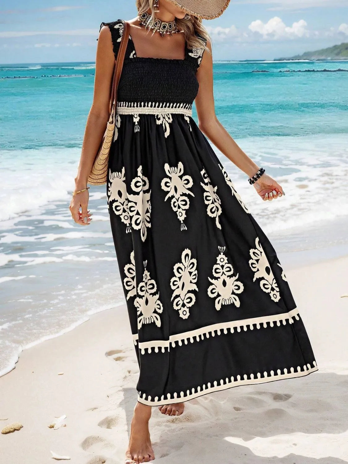 Trendsi Smocked Printed Maxi Dress with Wide Straps worn by a model on the beach, showcasing its flowing style and rich print in a stunning seaside setting.
