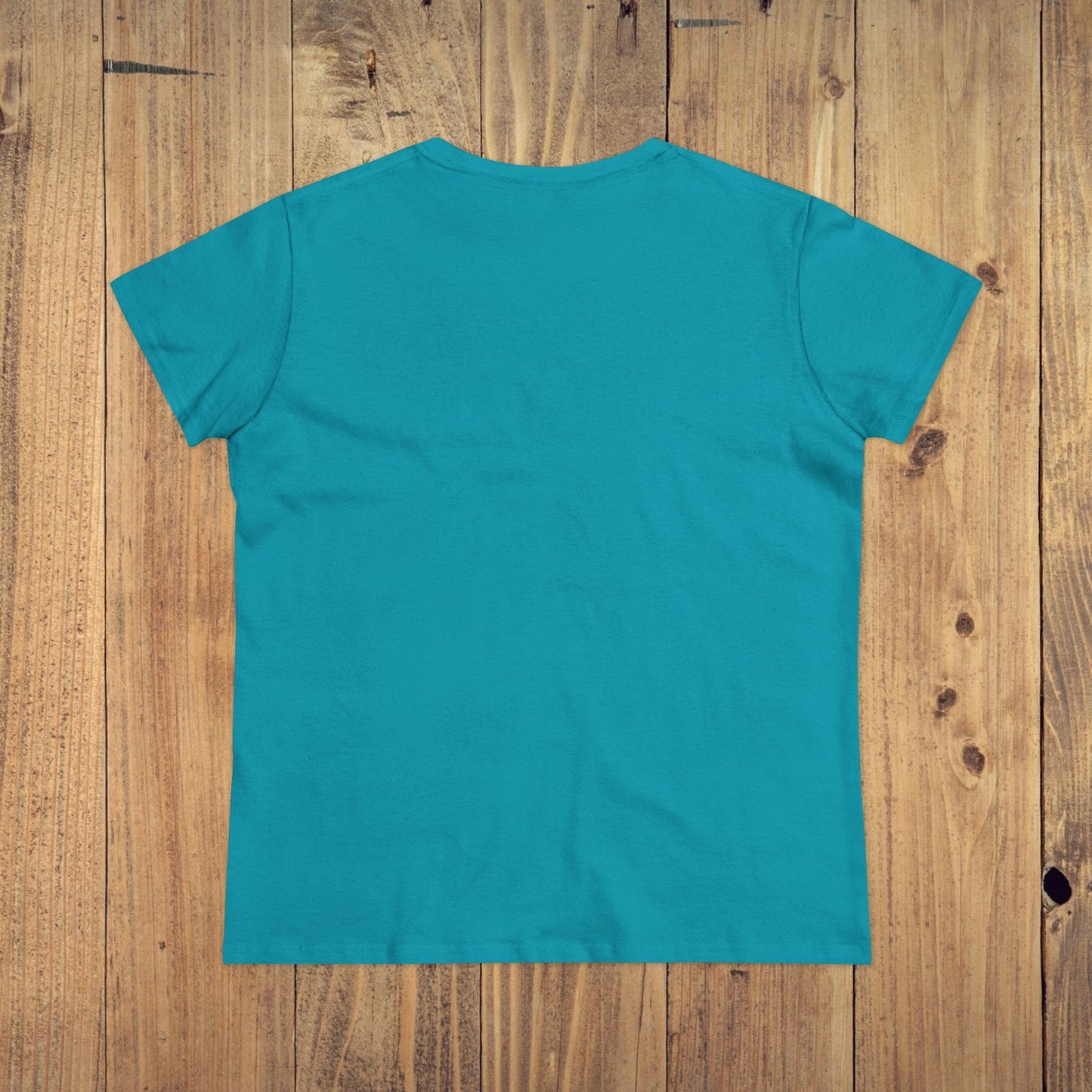 Back view of Stay Grounded Spiritual Tee in vibrant turquoise, designed for comfort at festivals and vacations, set against a wooden background.
