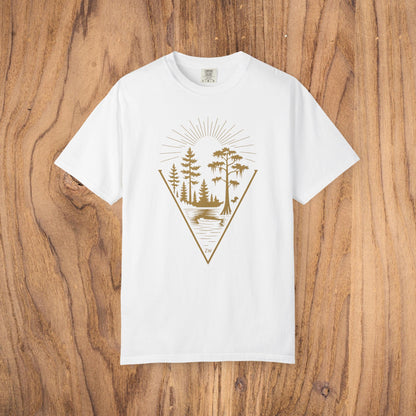 Nature Outdoor Vibes Tee on a wooden background, displaying a unique graphic design of trees and a lake in gold on a white shirt, made from soft 100% US cotton for ultimate comfort.