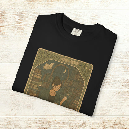 Page Turner Tarot Tee in black color featuring a vintage illustration of a woman reading amidst books, soft cotton material, sizes S to 4XL, eco-friendly and comfortable.