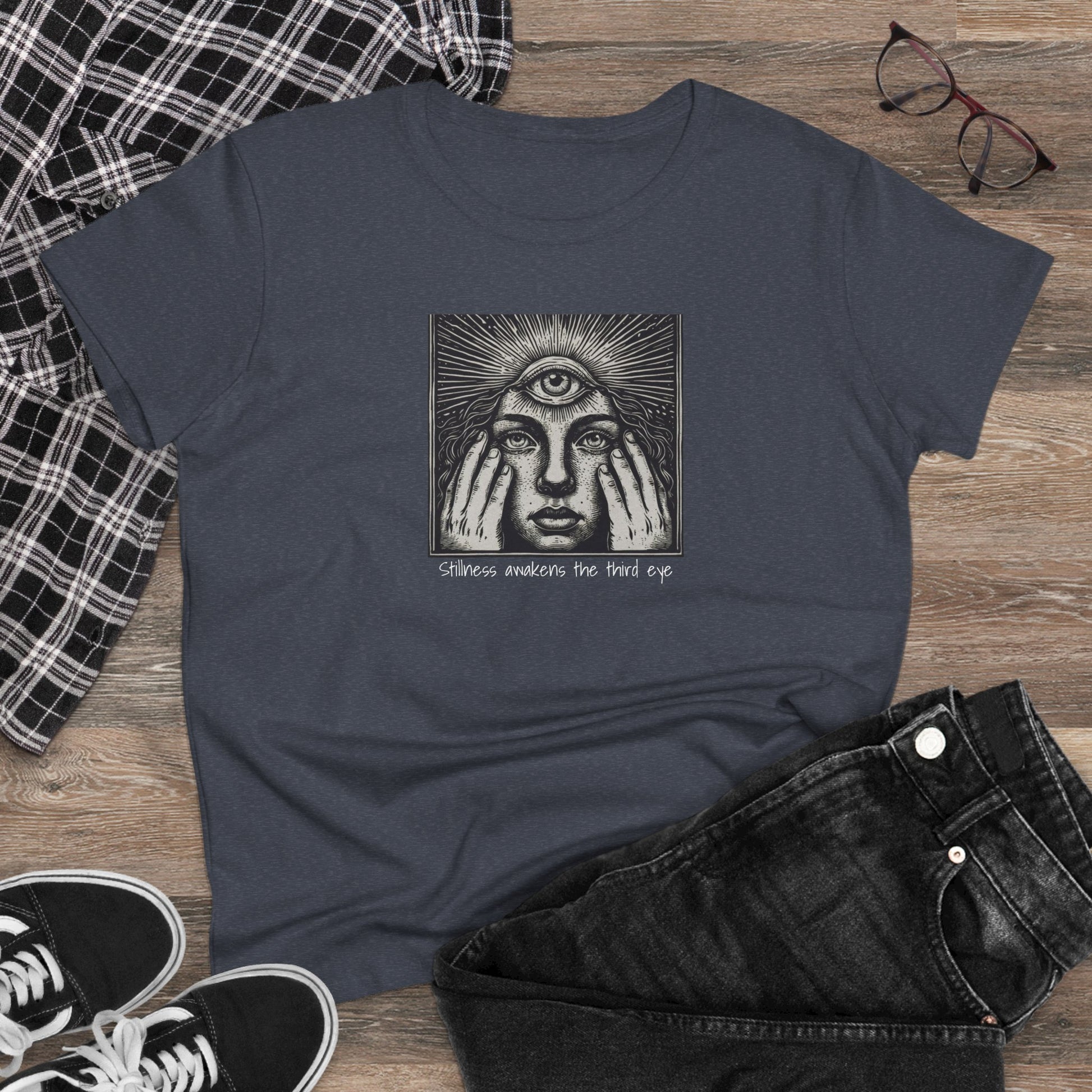 Stylish Third Eye Graphic Tee laid flat on a wooden surface, styled with black jeans and sneakers, showcasing the eye-catching graphic and text that represent awakening the third eye.