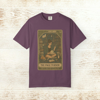 Page Turner Tarot Tee - A stylish purple soft cotton t-shirt displaying an enchanting illustration of a reader in a cozy library, available in sizes S to 4XL.