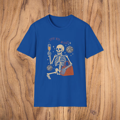 Spooky Spirits Graphic Tee in vibrant blue, featuring a whimsical skeleton with a drink and handbag. This comfortable 100% cotton tee is perfect for Halloween and is Oeko-Tex certified.