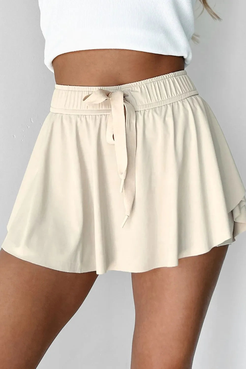 Chic Drawstring High Waist Lined Active Skorts in neutral tone, designed with a drawstring for adjustable fit, combining style and functionality for athletic activities.
