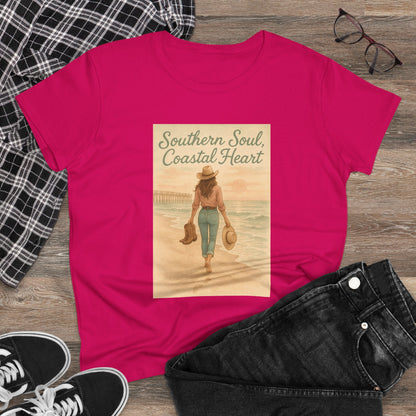Southern Soul Coated Heart Tee displayed on a wooden surface, featuring a vibrant pink color and an artistic print of a woman walking towards the ocean, embodying a relaxed coastal vibe. Perfect for casual wear.