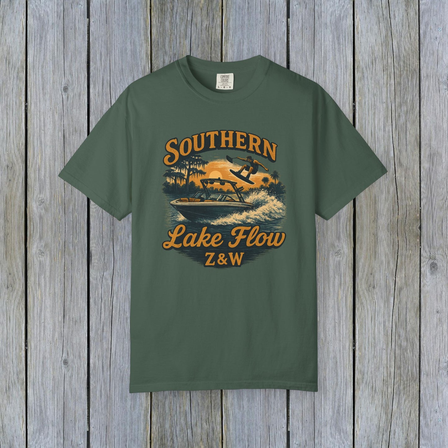 Southern Lake Flow T-Shirt in dark green, featuring a colorful graphic of an adventurous water skier, made with eco-friendly 100% US cotton, available in sizes S to 4XL.