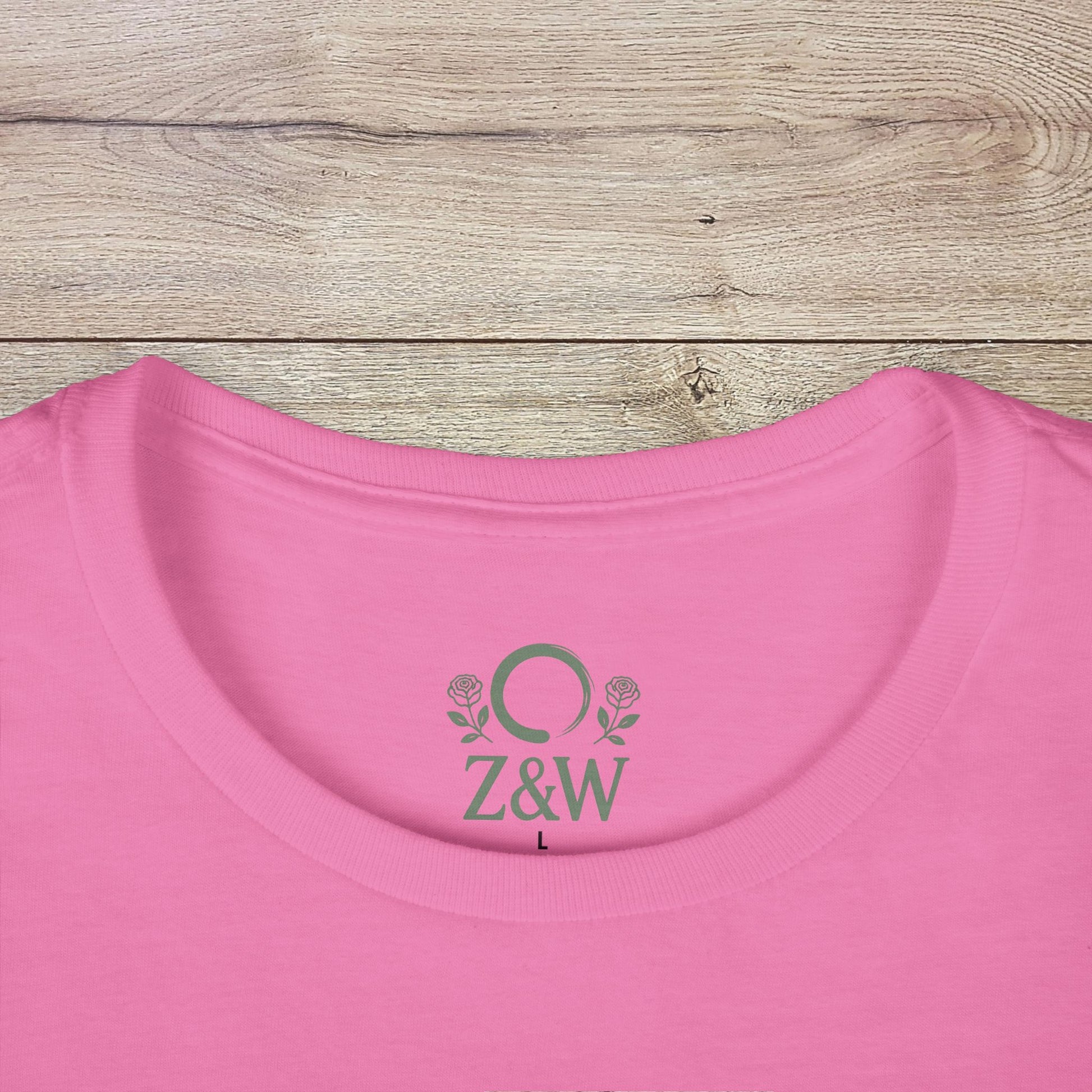 Wildflowers T-Shirt featuring a ribbed collar and a logo on the back, presented in soft pink color on a wooden table.