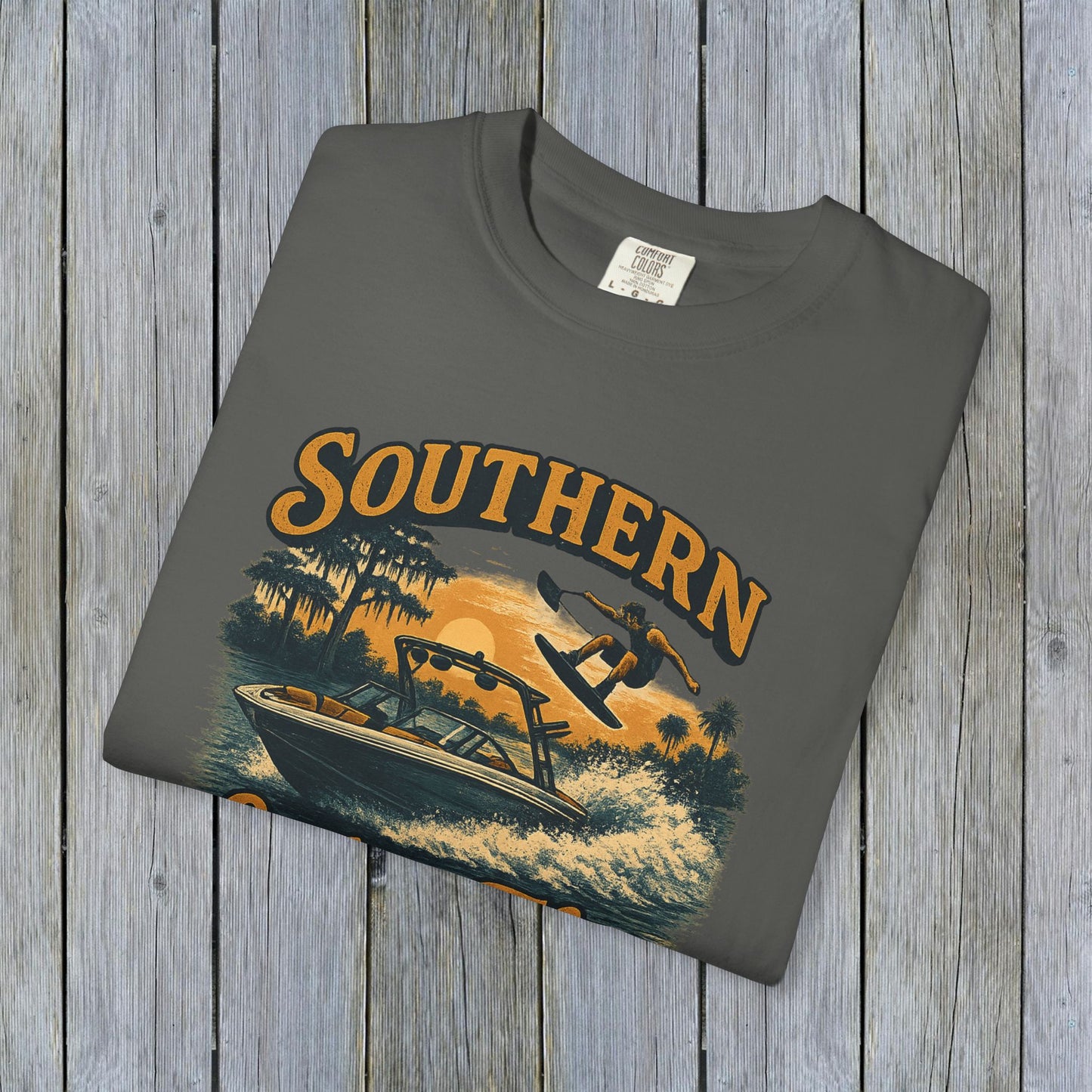 Southern Lake Flow T-Shirt displayed flat on a rustic wooden background in charcoal gray, featuring a water sports graphic, crafted sustainably with 100% US cotton.