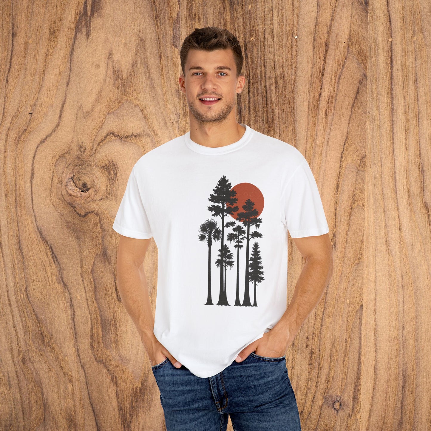Model posing in white Sunset Trees Unisex T-Shirt against a wood backdrop, highlighting the artistic design and relaxed fit for stylish outings.
