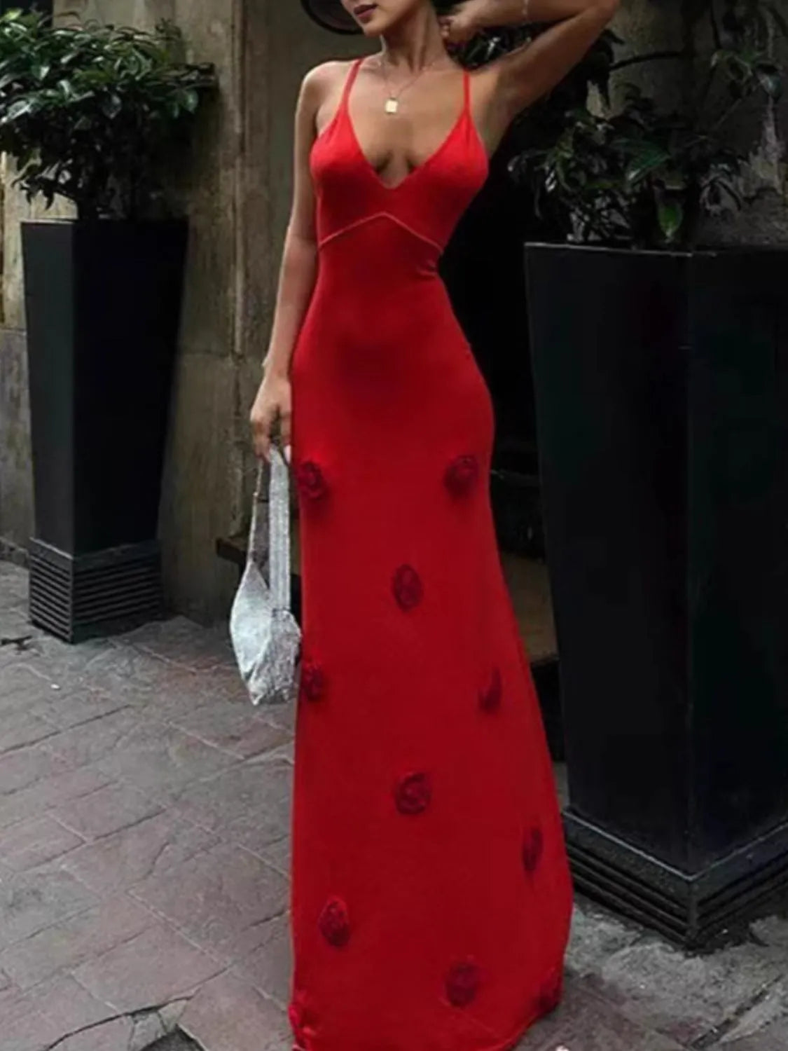 Chic model in a striking red backless flower print maxi sweater cami dress, standing outdoors against a backdrop of urban greenery. Slightly stretchy and made from 100% polyester for a form-flattering fit.
