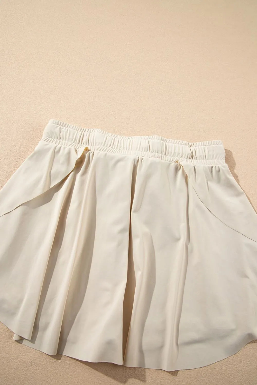 Flat lay of the Drawstring High Waist Lined Active Skorts highlighting the pleated design and breathable fabric texture.