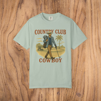 Country Club Cowboy Graphic Tee in light mint, illustrating a cowboy carrying golf equipment against a nature backdrop. Made from eco-friendly cotton, this shirt is both stylish and sustainable.