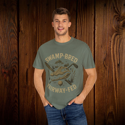 Model wearing the Unisex Swamp-Bred Fairway-Fed Tee in olive green, showcasing the unique design with a golf club and swamp scene, made for comfort and style.