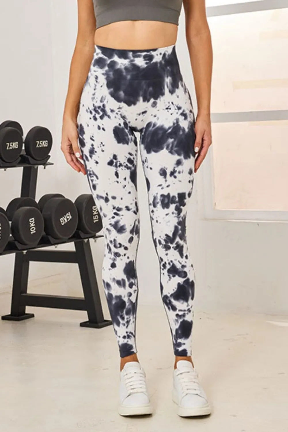 Front view of Slightly Stretchy Tie-Dye High Waist Active Leggings in white and navy pattern, displayed by a model in a workout environment.