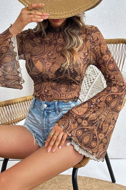 Chic view of a sheer printed mock neck top with flare sleeves, paired with denim shorts, capturing a trendy summer vibe.