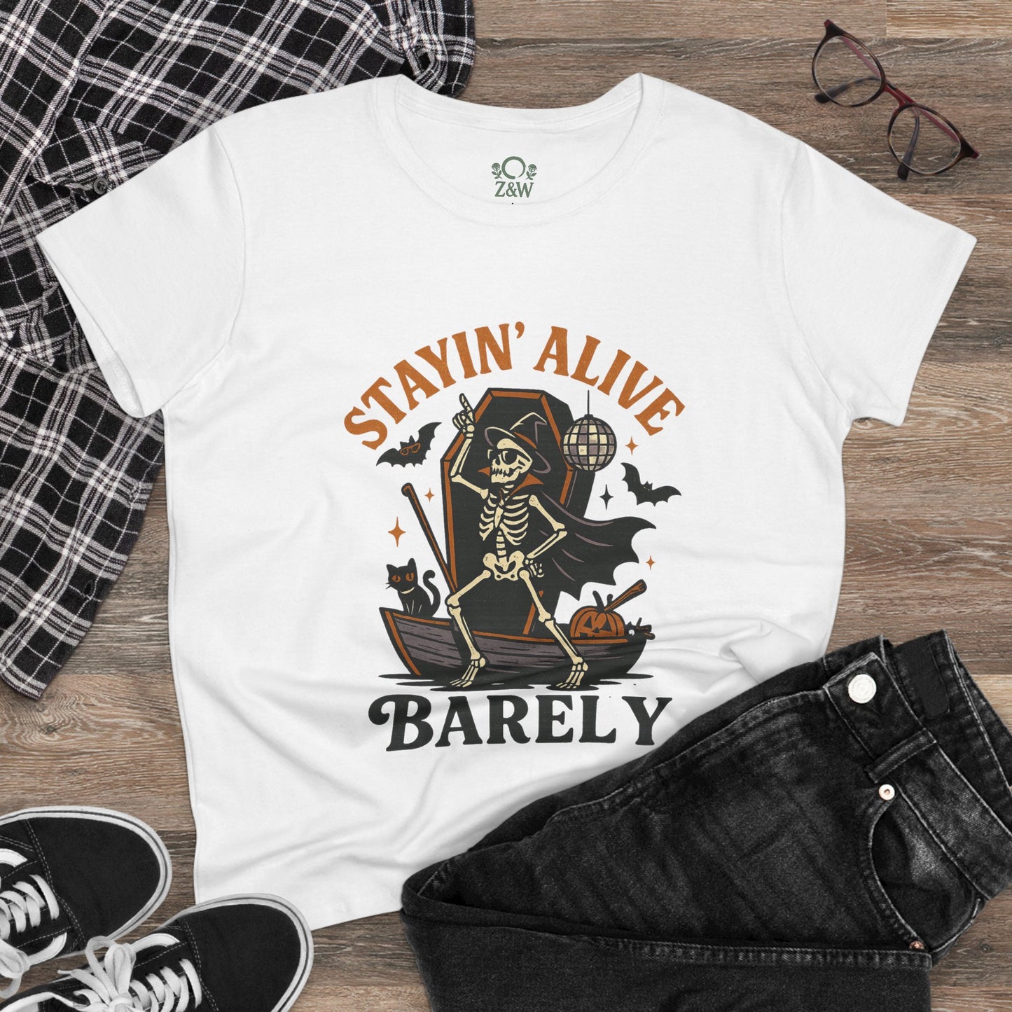Flat lay of the Stayin’ Alive T-Shirt styled with black jeans and glasses, showcasing a fun Halloween unisex tee.