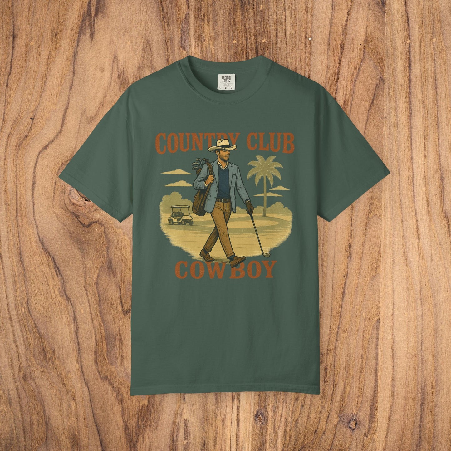 Country Club Cowboy Graphic Tee in dark green, showcasing a stylish cowboy with golf clubs and palm trees. Crafted from eco-friendly cotton fabric, perfect for golf enthusiasts.