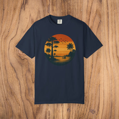 Unisex Garment-Dyed Sunset Tee in classic navy blue displaying a gorgeous sunset graphic featuring silhouettes of palm trees and birds. Crafted from soft 100% cotton, available in sizes S to 4XL.