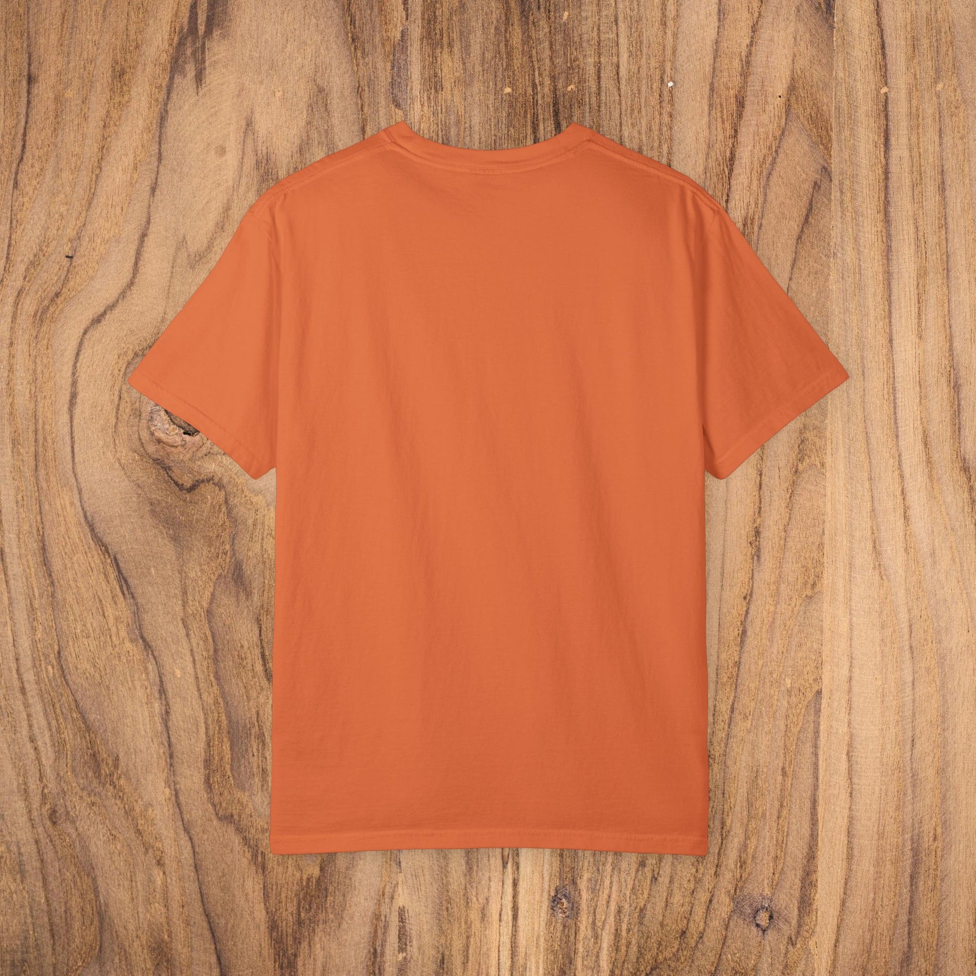 Back view of the orange Country Club Cowboy Graphic Tee on a wooden surface, showcasing the shirt's minimalist style.