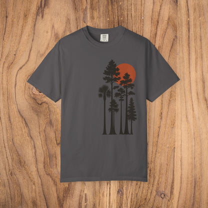Sunset Trees Unisex T-Shirt laid flat on a wooden background, highlighting the beautiful sunset tree design and the garment-dyed texture, ideal for casual and semi-formal occasions.