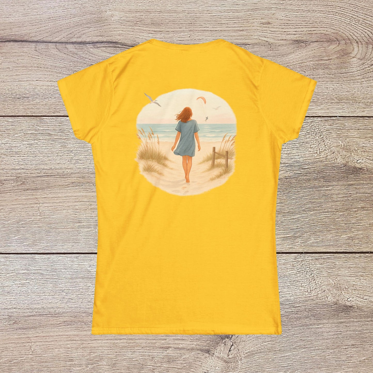 Back view of a woman wearing the vibrant yellow Women's Coastal Spirit Midweight Cotton Tee while strolling on the beach, capturing the essence of coastal lifestyle.