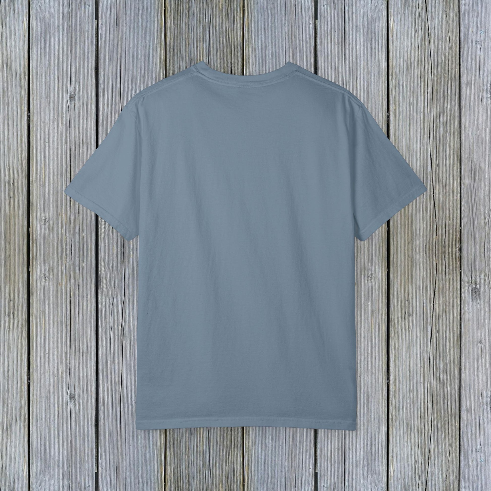 Back view of the Unisex Garment-Dyed Lake Rules Tee, displaying a soft fabric texture in a blue hue against wooden planks.