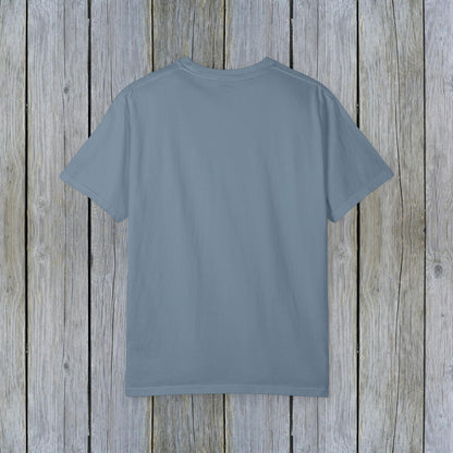 Back view of the Unisex Garment-Dyed Lake Rules Tee, displaying a soft fabric texture in a blue hue against wooden planks.