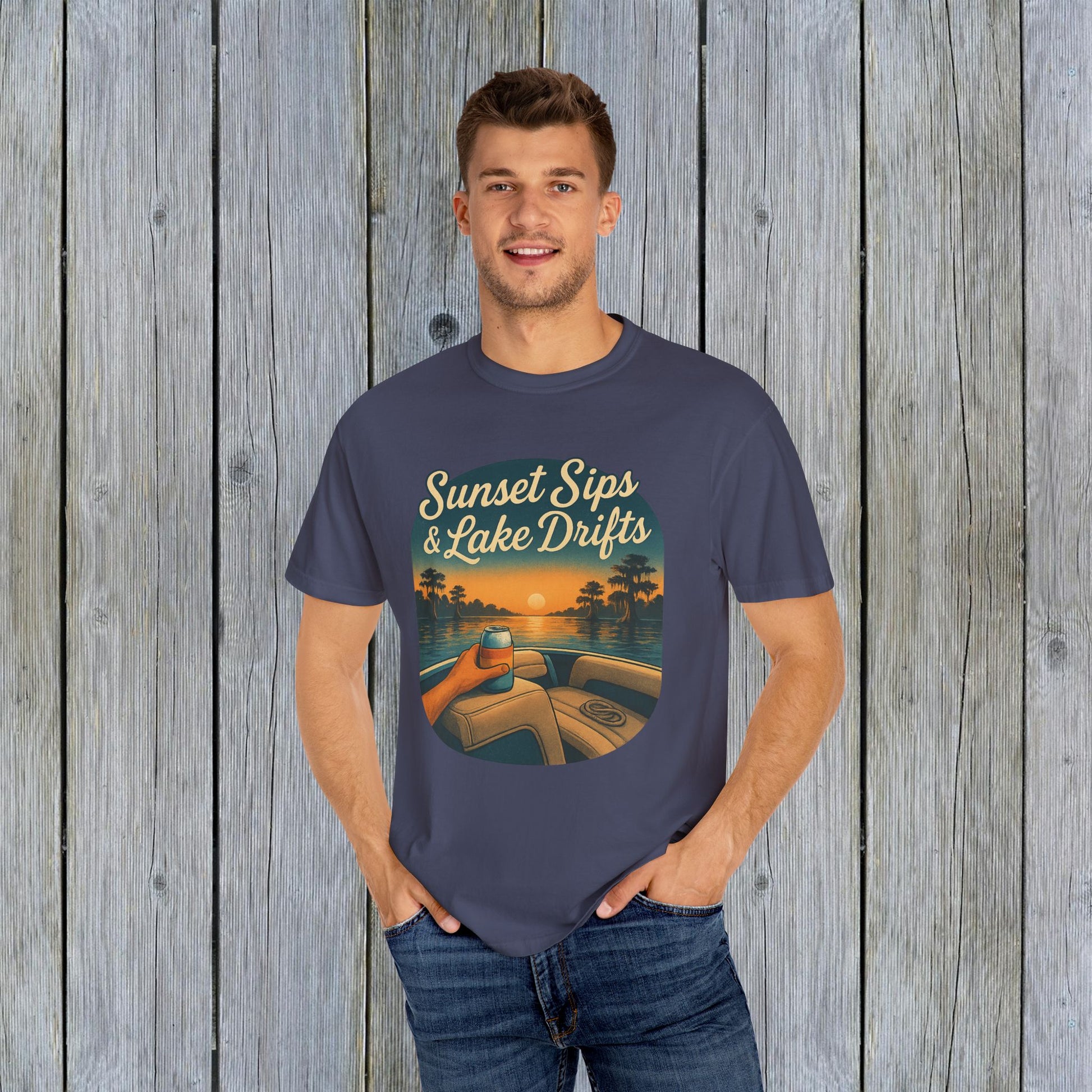 Model wearing Lake Drifts T-Shirt in dark blue, showcasing the 'Sunset Sips & Lake Drifts' design against a rustic wood backdrop.