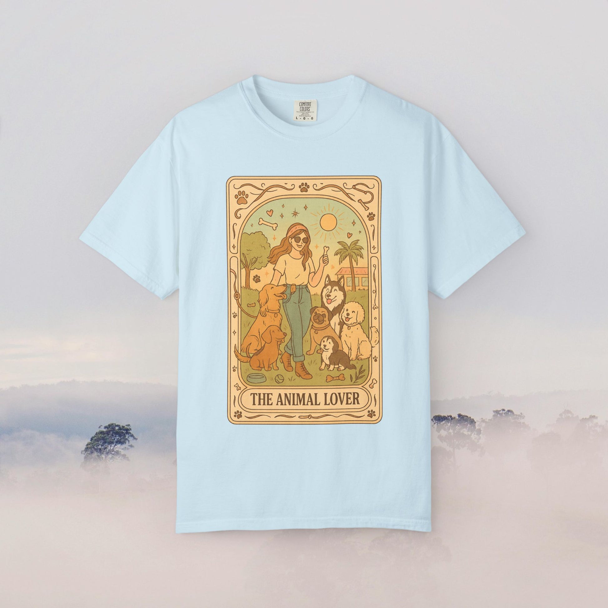 Animal Lover Tarot Tee in light blue color featuring a whimsical graphic with a woman surrounded by various animals, perfect for animal enthusiasts.