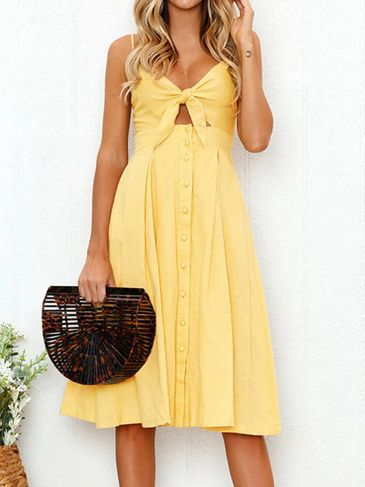 Cutout Smocked Sweetheart Neck Cami Dress with Decorative Button and Opaque Design, showcased in a sunny yellow color, featuring a tied front and button details on a model.