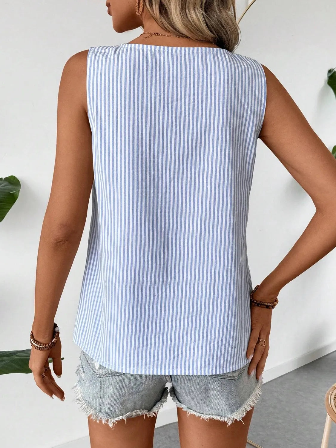 Back view of the Asymmetrical Striped Tank with Decorative Buttons for Women in blue stripes, showcasing a casual and relaxed fit, made from 100% polyester.