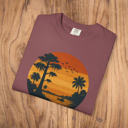 Unisex Garment-Dyed Sunset Tee in a rich maroon shade featuring an artistic sunset scene with palm trees, made from soft 100% cotton for comfort.