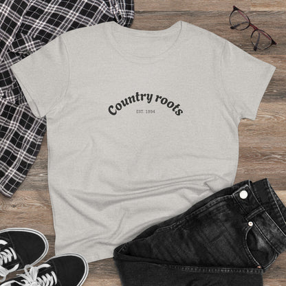 Country Roots Cowgirl Tee featuring a stylish 'Country roots EST. 1994' design, laid flat on rustic wooden background with casual outfit elements.