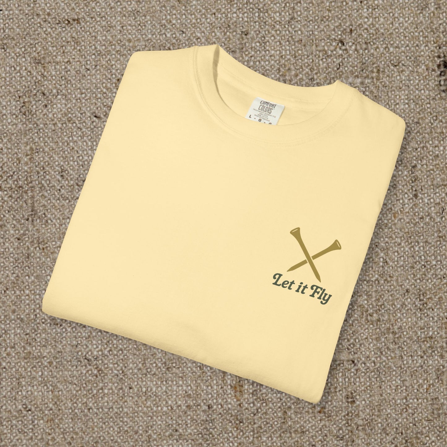 Flat lay of the yellow Tee It High Let It Fly Graphic Tee, emphasizing the minimalist graphic of crossed golf tees and the slogan.