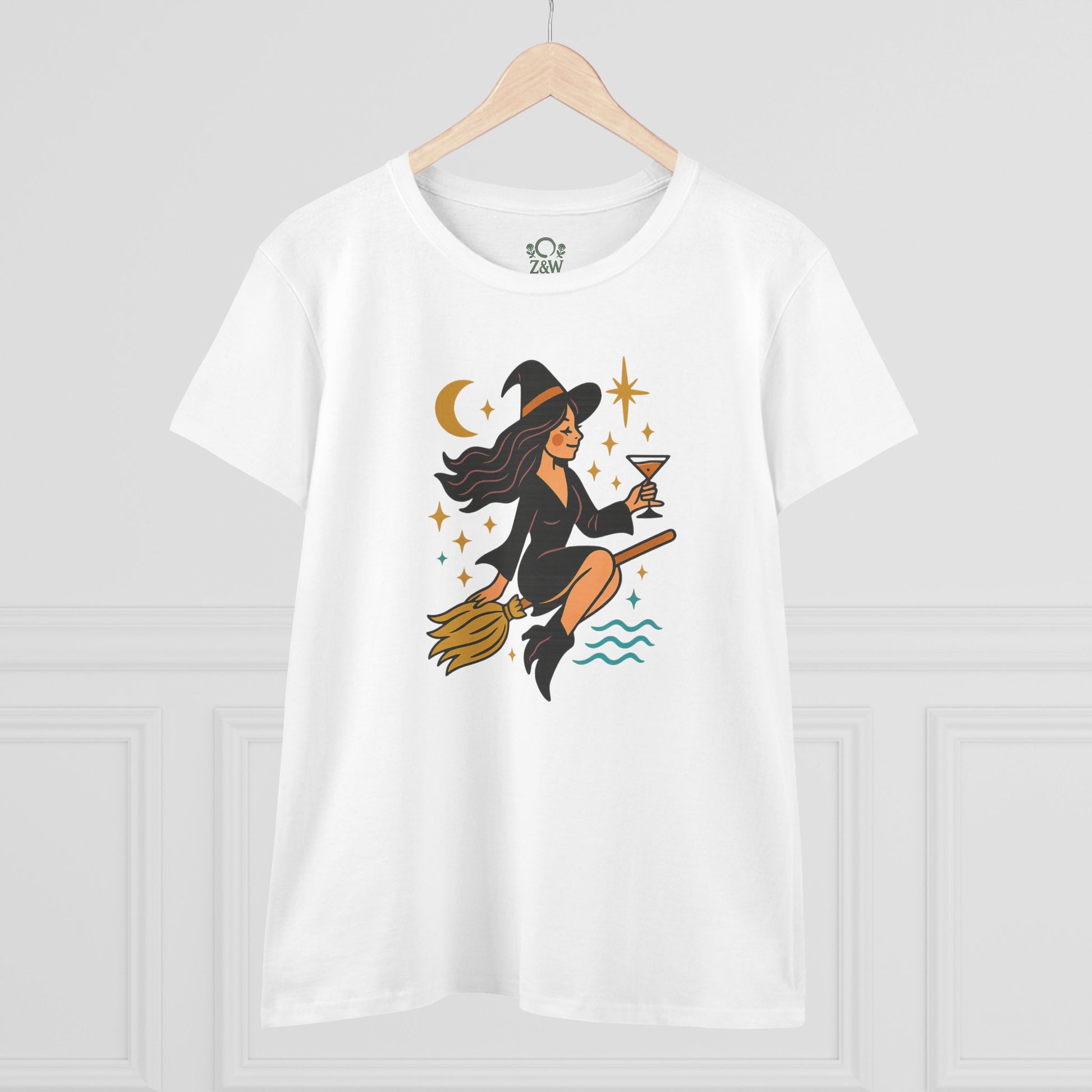 Witchy Night Out Tee - A stylish white t-shirt adorned with a whimsical illustration of a witch sipping a cocktail while flying on a broomstick.