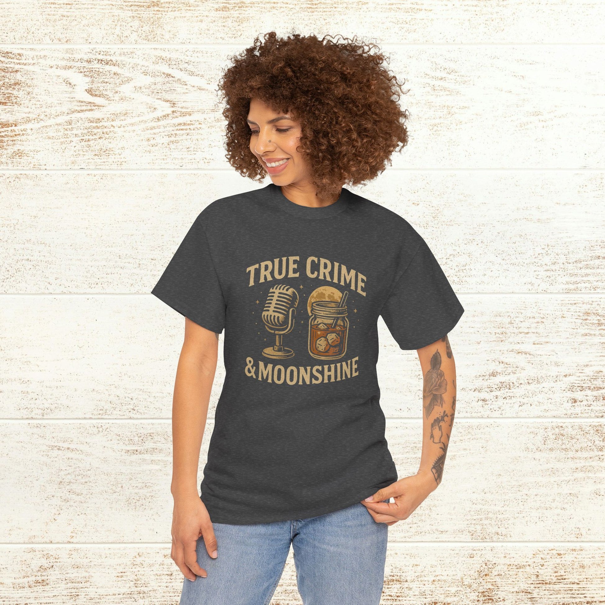 Model wearing the True Crime & Moonshine Unisex Graphic Tee against a rustic wooden backdrop, highlighting its unique design for true crime enthusiasts.