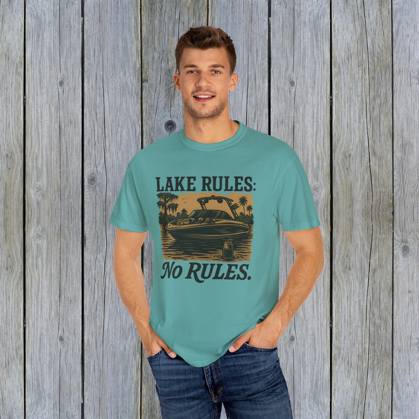 Stylish man wearing a teal Unisex Garment-Dyed Lake Rules Tee with a boat design, ideal for casual outdoor activities and gatherings.