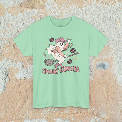 Spooky Cowgirl Graphic Tee in mint green, showcasing a cheerful ghost in a cowboy hat with a broomstick and vinyl records. Soft, sustainable fabric available in sizes S-5XL.