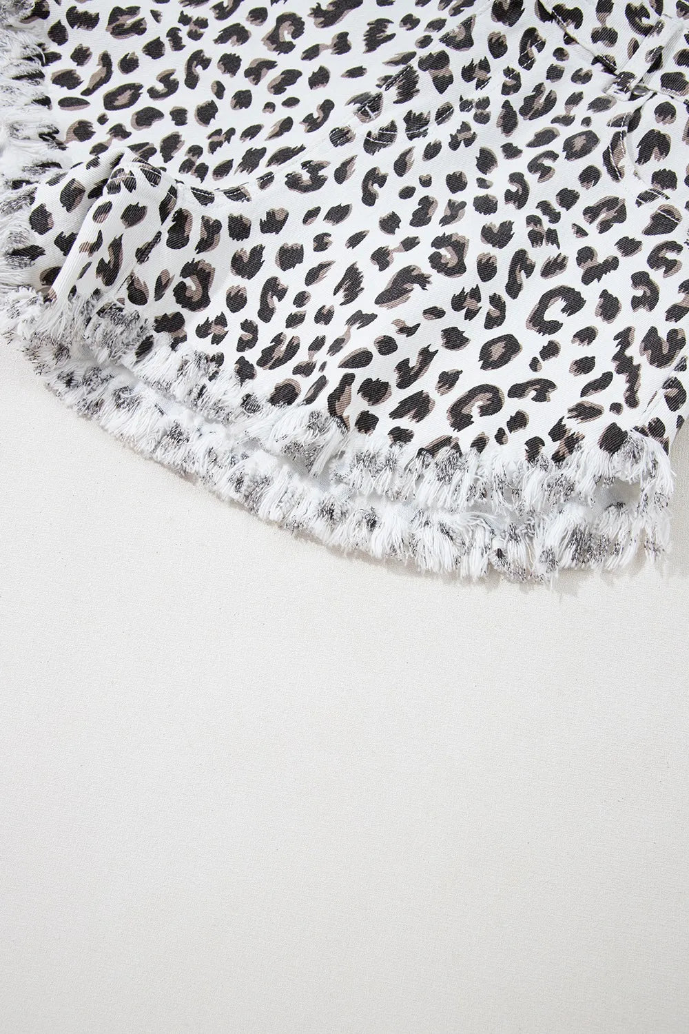 Bottom edge of Leopard Frayed Hem Denim Shorts - Highlighting frayed edges and unique leopard print.