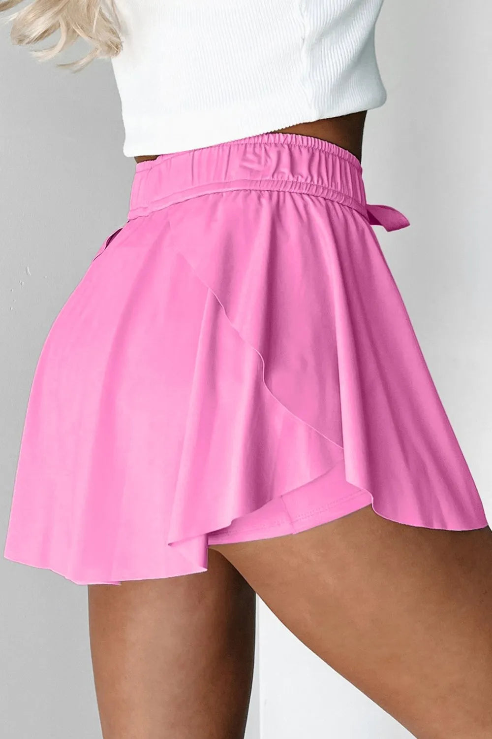 Side view of the Drawstring High Waist Lined Active Skorts in pink, emphasizing the stylish flared silhouette and drawstring detail.